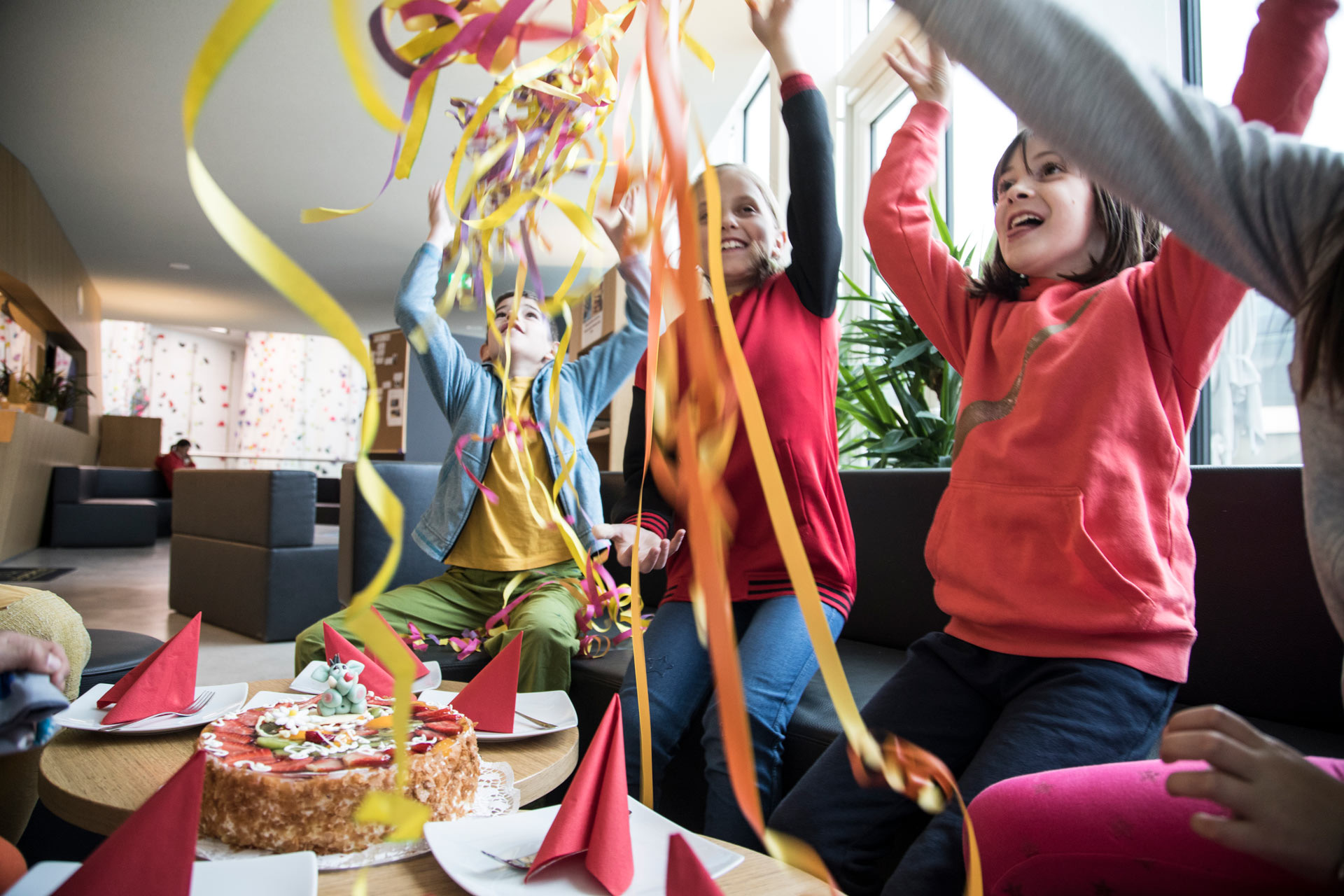 Kinder feiern Geburtstag mit Torte und Luftschlangen