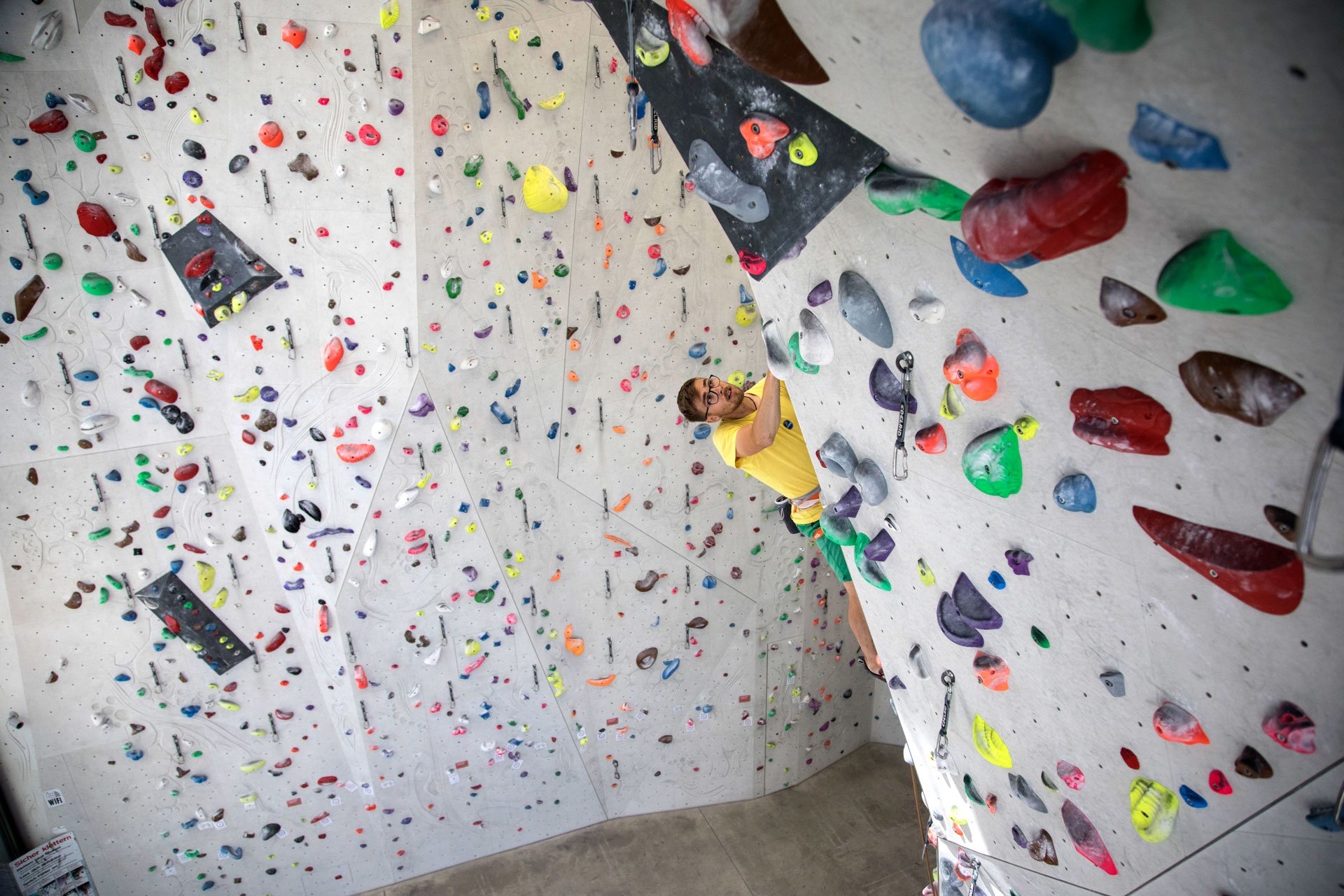 Kletterer in einer bunten Route an der Hallenwand