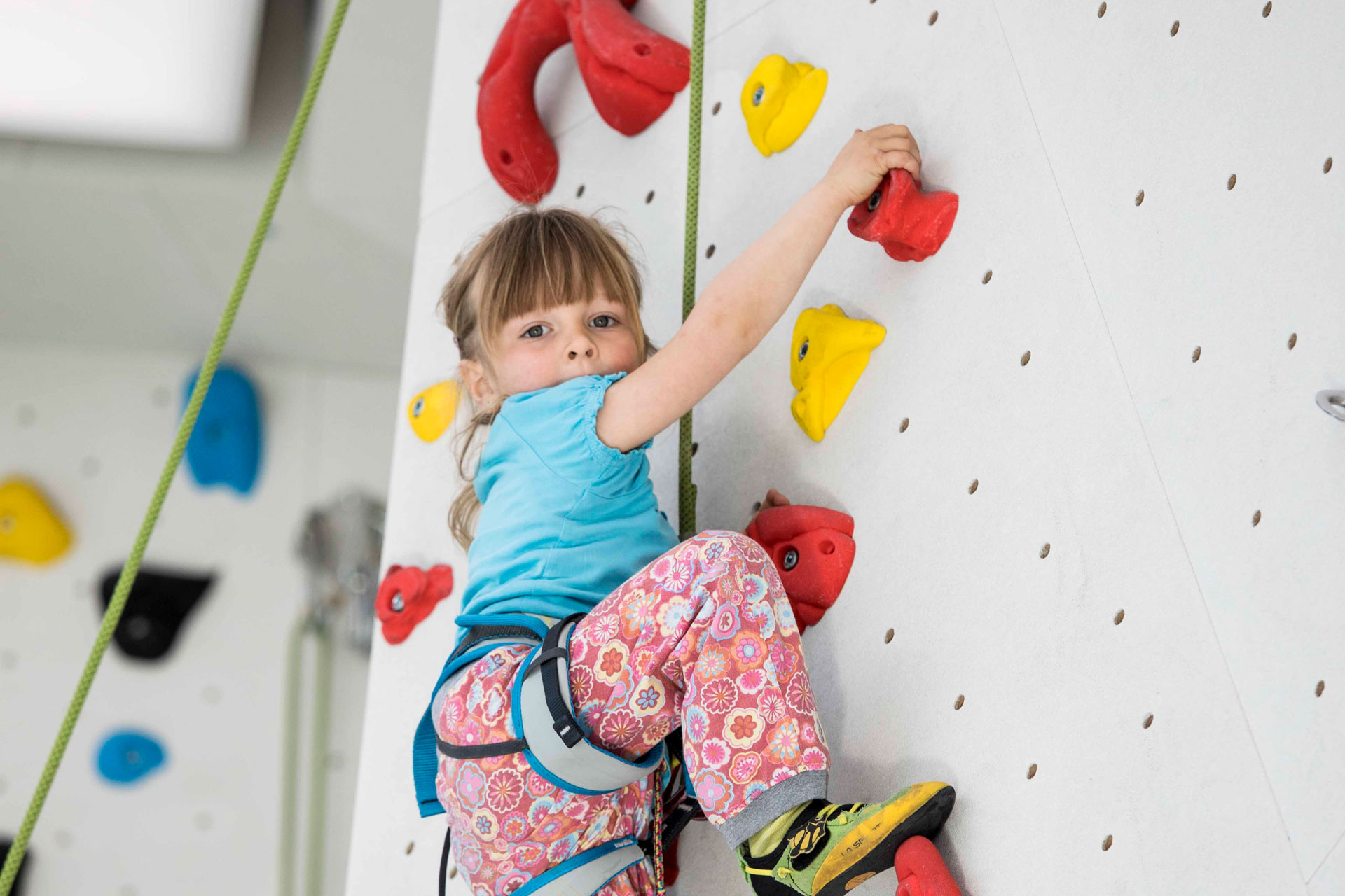 Kleines Mädchen klettert an einer bunten Wand